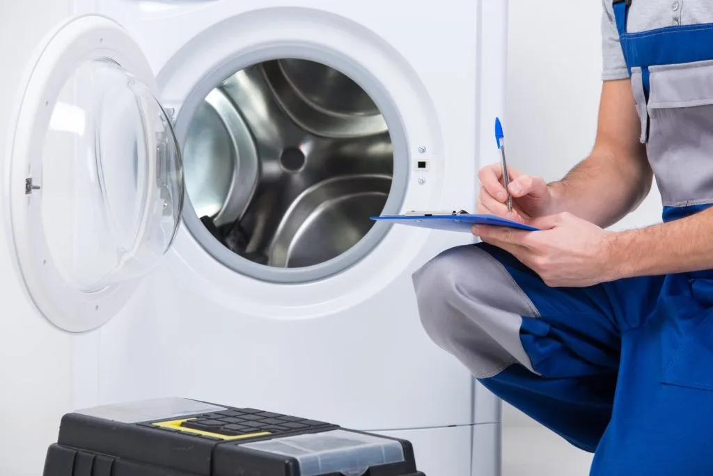 Repairman Repairing Dryer In Calgary And Writting With A Pen