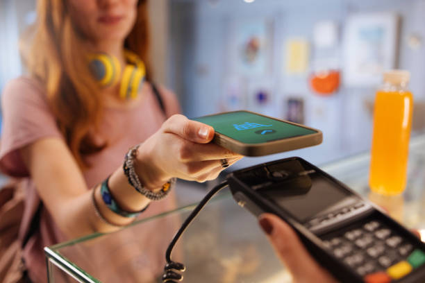 Young woman using smartphone for mobile payment and receiving credit back at SMS Appliances store.